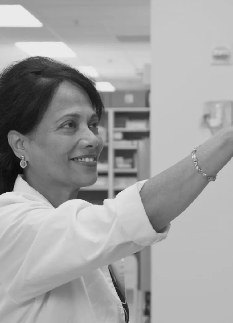 Une scientifique en blouse de laboratoire présente un flacon, illustrant son travail de recherche.