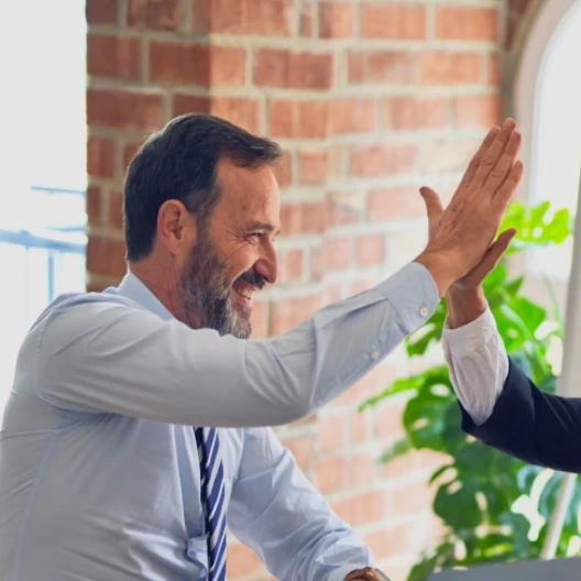 Deux professionnels se félicitent en se donnant un high five, symbolisant la réussite et la collaboration